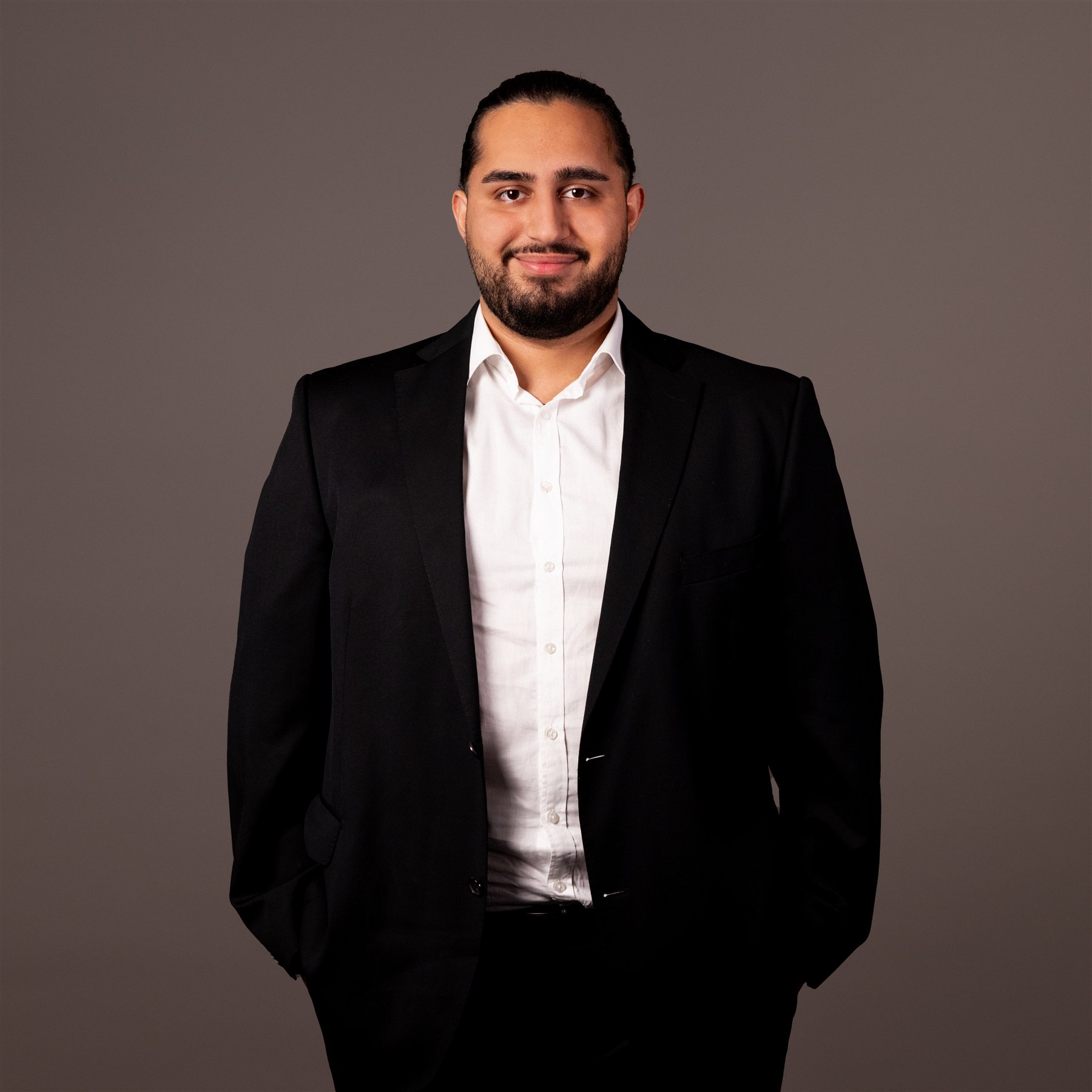 Danial Shiekho, Portrait im dunklen Sakko vor neutralem Hintergrund